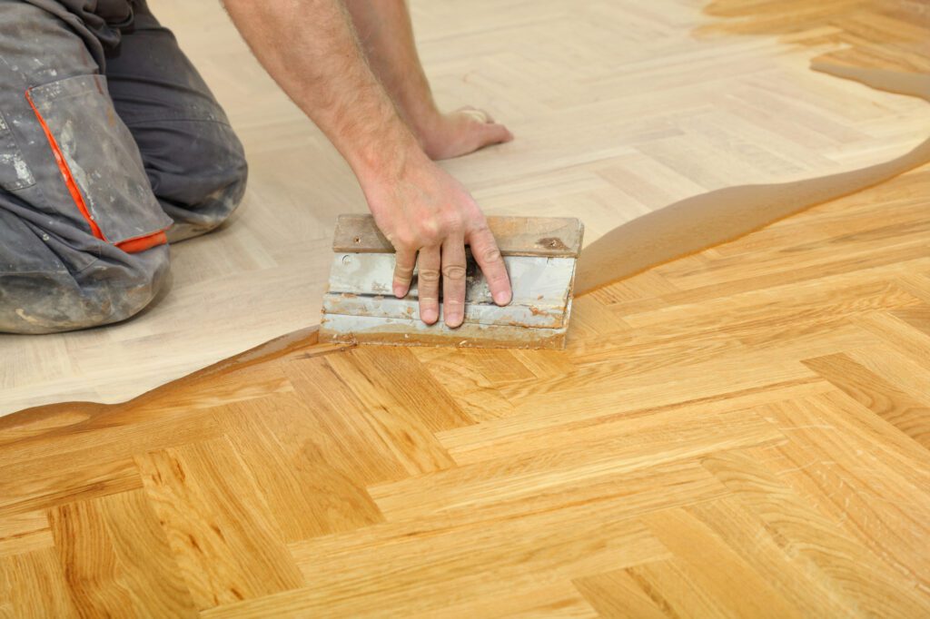 Varnishing of oak parquet floor, workers hand and tool