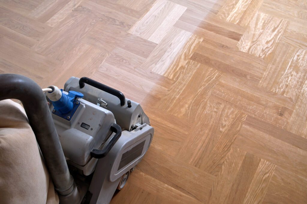 Sanding hardwood floor with the grinding machine. Repair in the apartment. Carpenter doing parquet wood floor polishing maintenance work by grinding machine